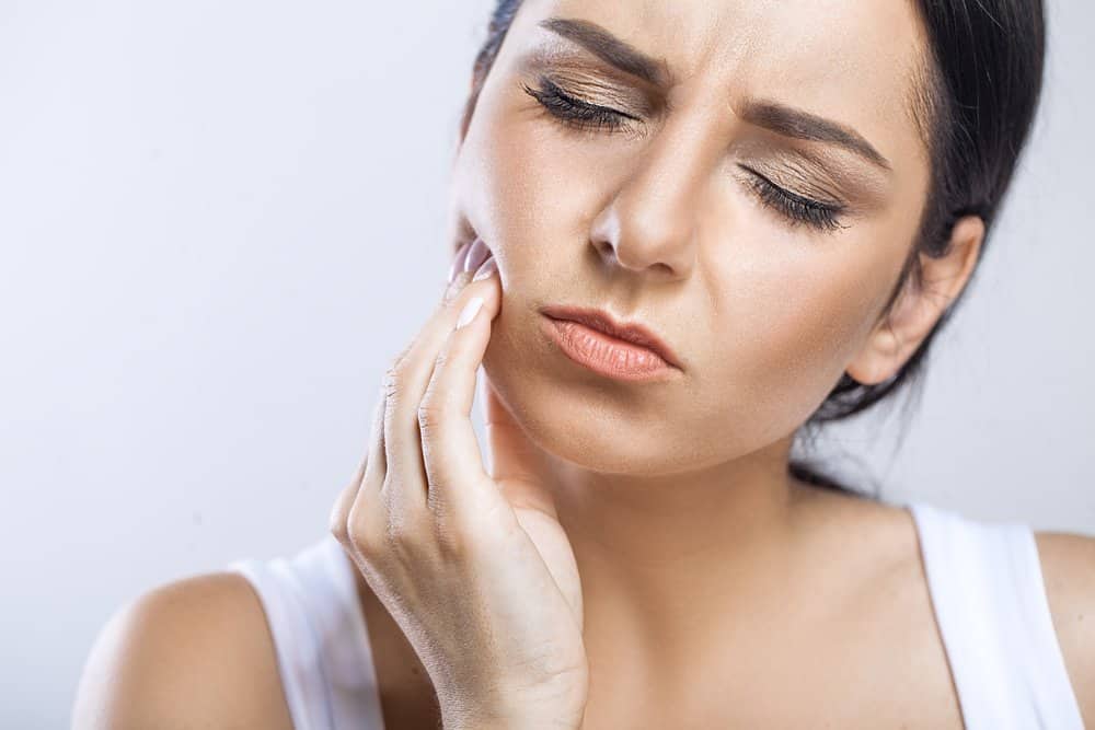 Woman rubbing jaw in pain.